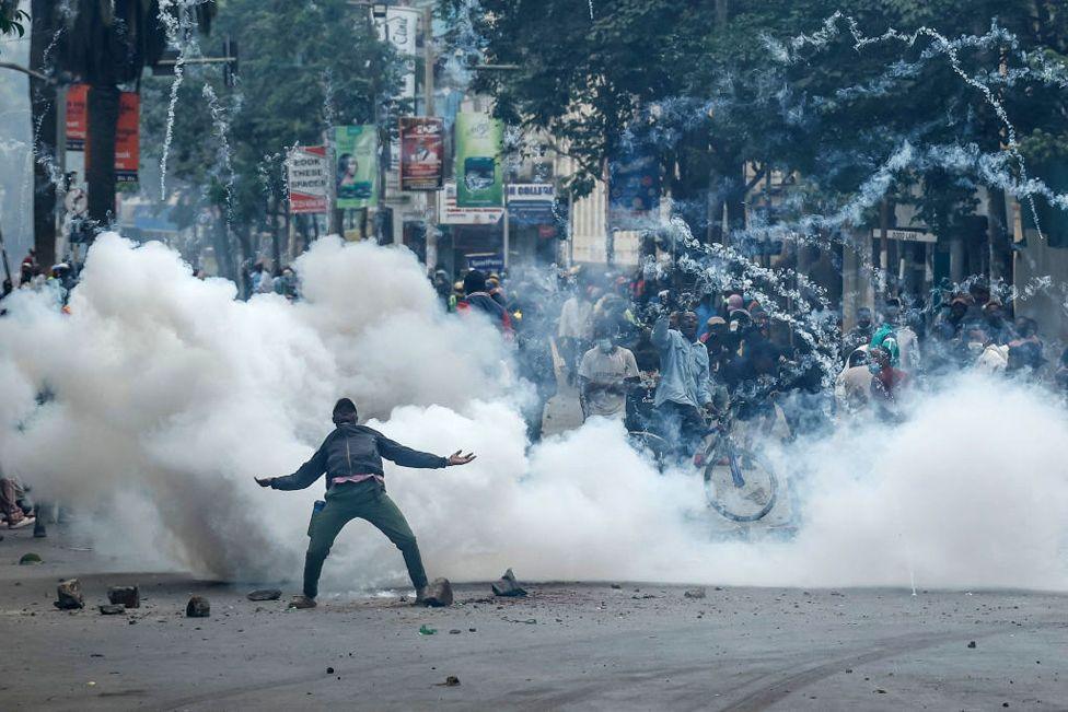 A teargas canister detonates as a protester gestures at Kenyan anti-riot police officers during anti-government protests in Nairobi