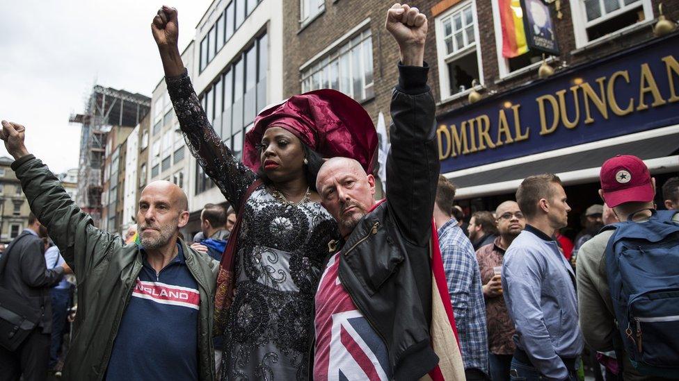 People in London hold their fist in the air during a vigil for hate crime victims