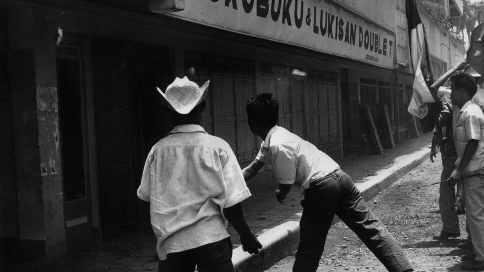 Muslim students in Jakarta, Indonesia, attack a Communist bookstore after an aborted communist coup, October 1965.