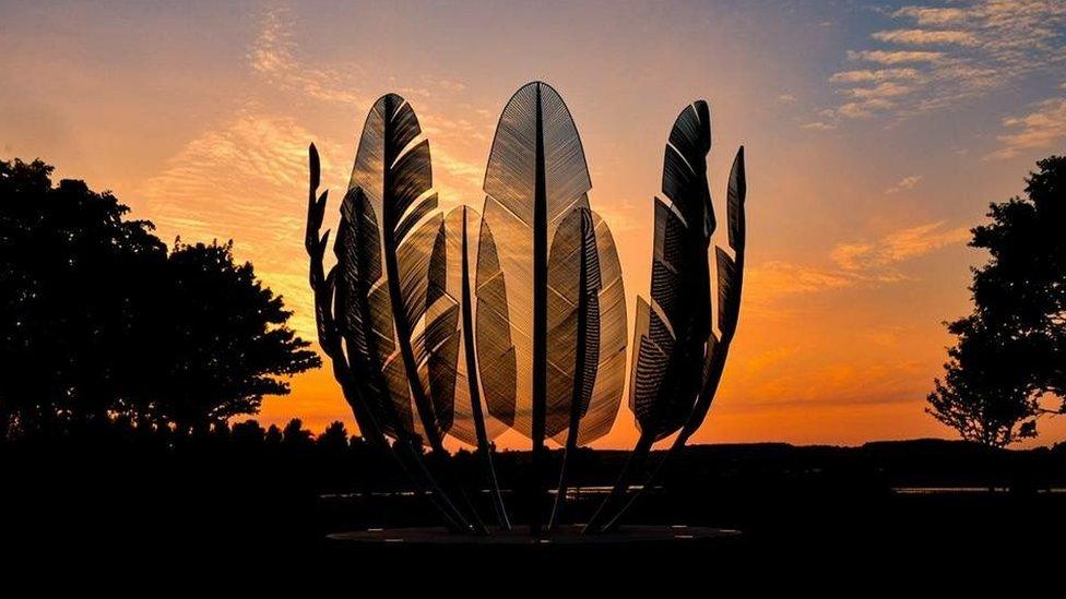 sculpture with an orange sunset behind