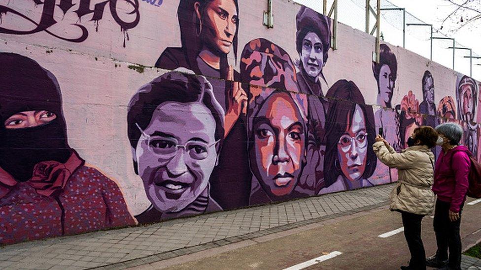 A woman takes pictures to a feminist mural in Madrid