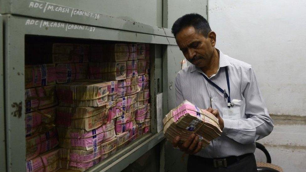 An Indian bank employee looks at deposited old denomination 1000 rupee currency notes in a bank vault in Ahmedabad on November 11, 2016.