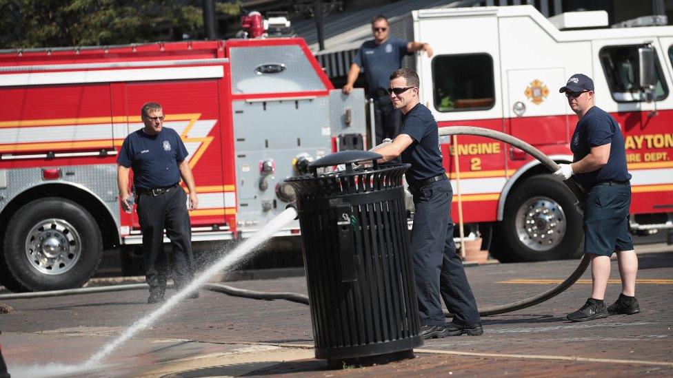 Firefighters clean the sidewalk following a mass shooting on August 04