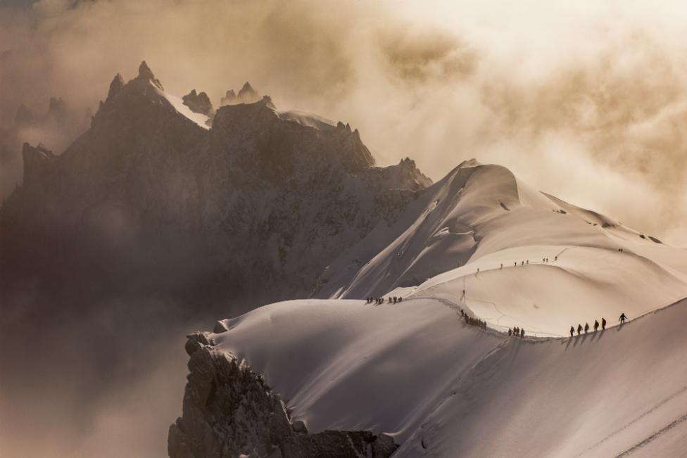 Climbers descend a snow ridge on the French Alps