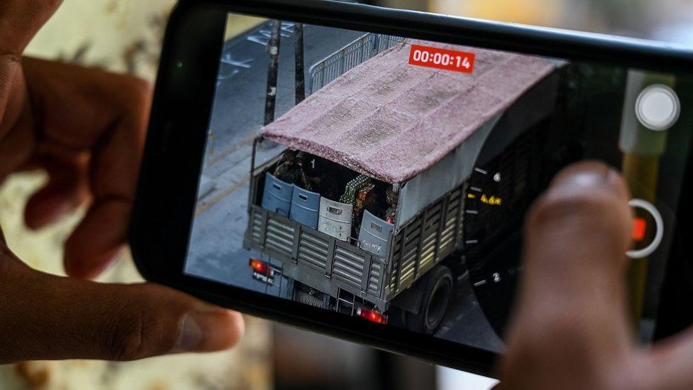 A person holds a mobile phone showing a video of soldiers looking out from a truck in Yangon on February 28, 2021