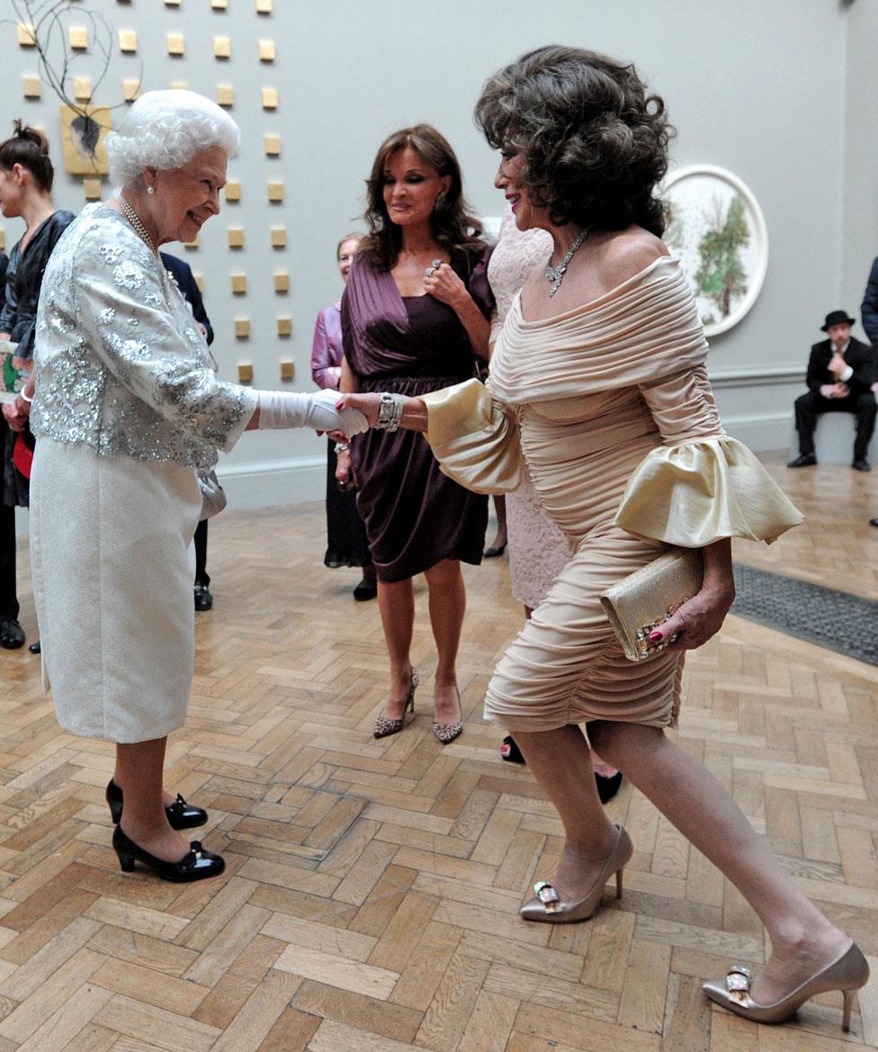 HRH Queen Elizabeth II meets a curtseying Joan Collins at a special 'Celebration of the Arts' event at the Royal Academy of Arts in 2012 in London