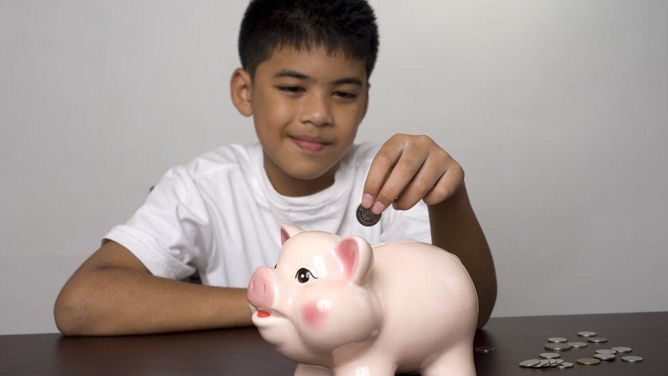 boy-putting-money-in-a-piggy-bank.