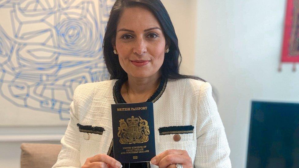 Home Secretary Priti Patel holding a blue passport