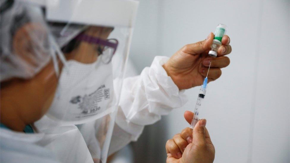 woman with needle measuring vaccine.