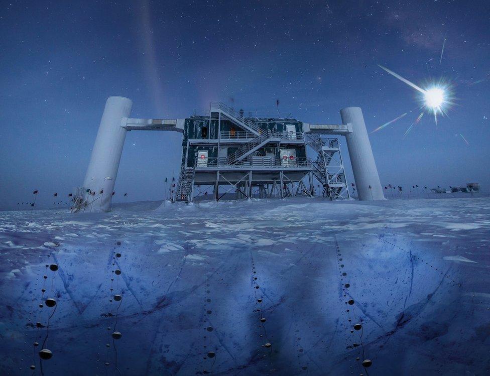 The IceCube facility, a structure built atop the ice in Antarctica. The picture is taken at nighttime, the moon a bright glow in the sky