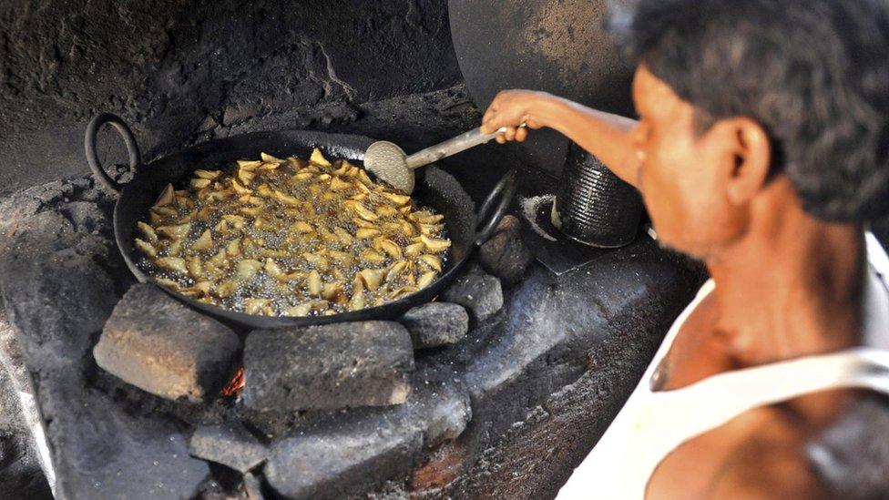 An Indian worker fries samosas