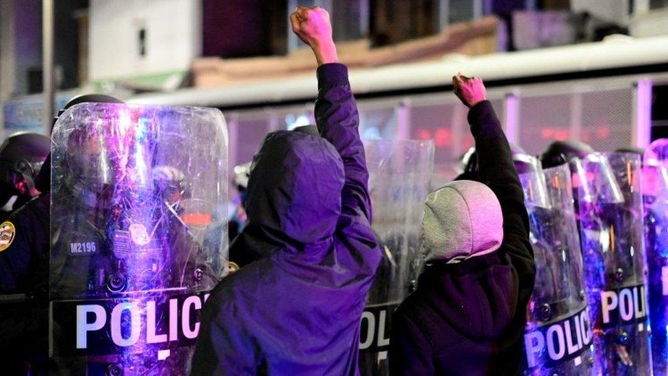 Protesters stand in front of a police barricade