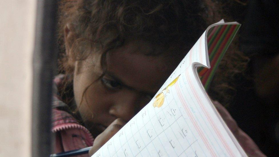 A Yemeni young girl writes in an exercise book inside a minibus turned into a mobile classroom in Sanaa