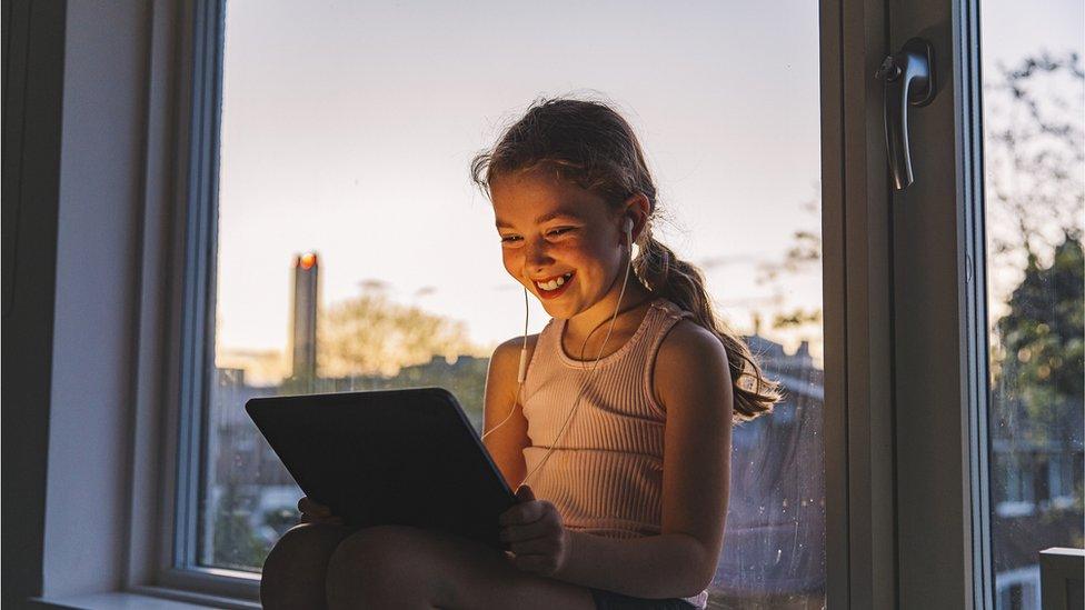 A young girl watches her Ipad