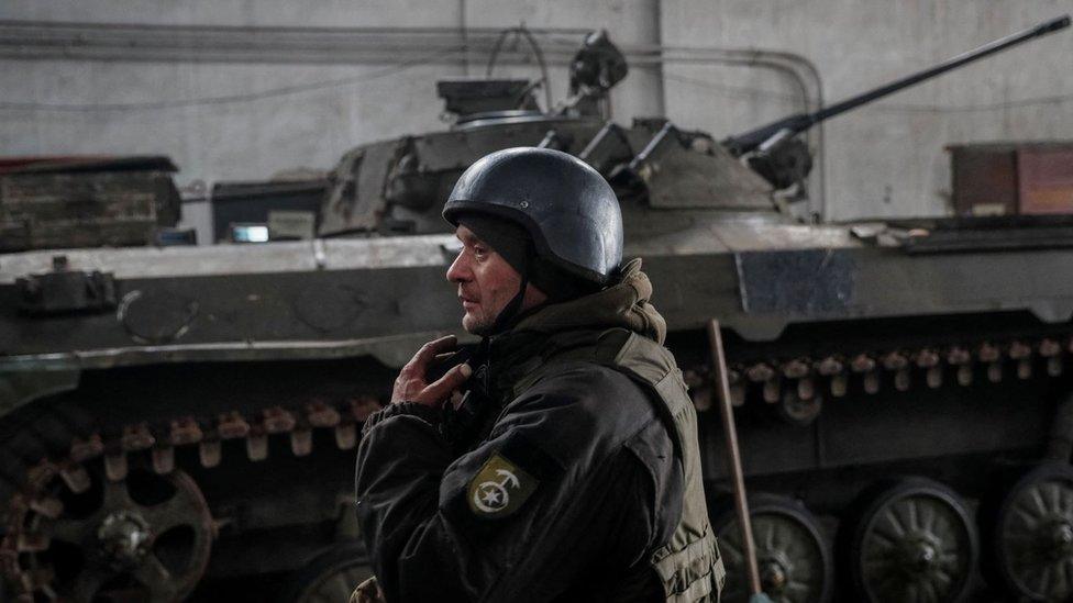 A member of the Ukrainian armed forces stands near an armoured vehicle near the city of Novoluhanske in the Donetsk region