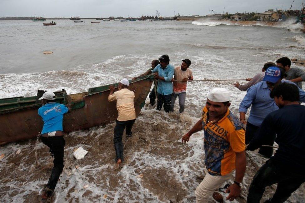 Fishermen move a fishing boat to a safer place along the shore ahead of the expected landfall of Cyclone Vayu at Veraval, India, June 12, 2019