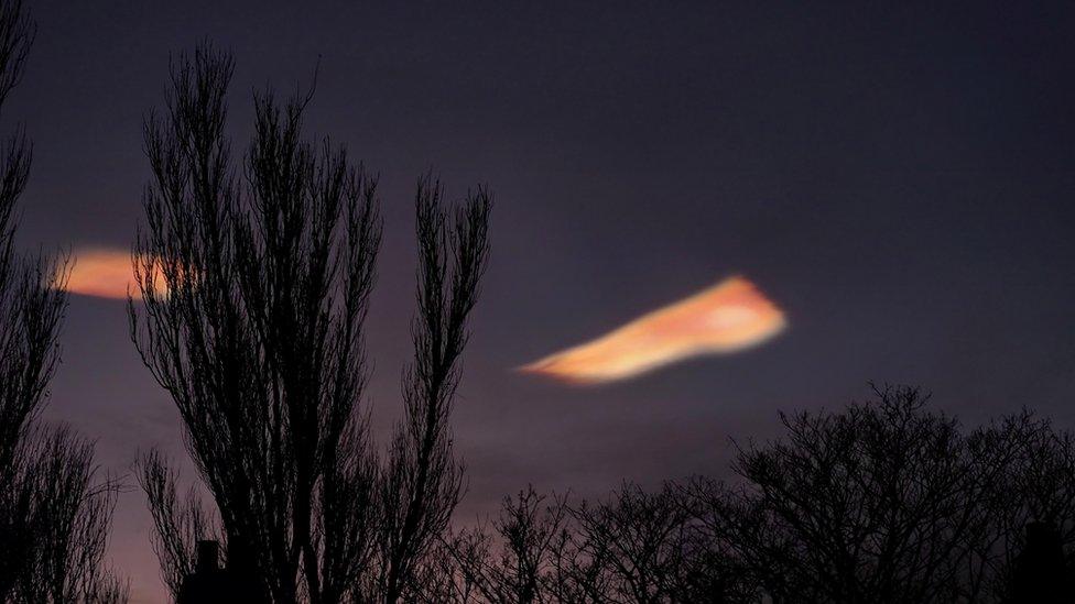 Rainbow colour cloud shining bright with a darkened sky during sunset