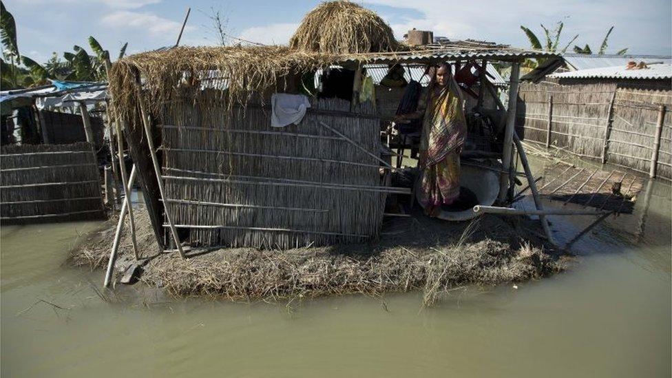 An Indian woman stands in a shelter surrounded by flood waters in Morigaon district, east of Gauhati, northeastern Assam state, India, Sunday, July 31, 2016