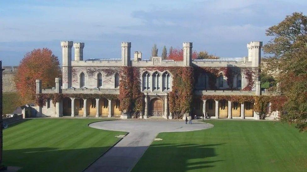 Front view of the ivy-covered historic Lincoln Crown Court building inside the castle grounds with paving and a lawned area in the foreground.