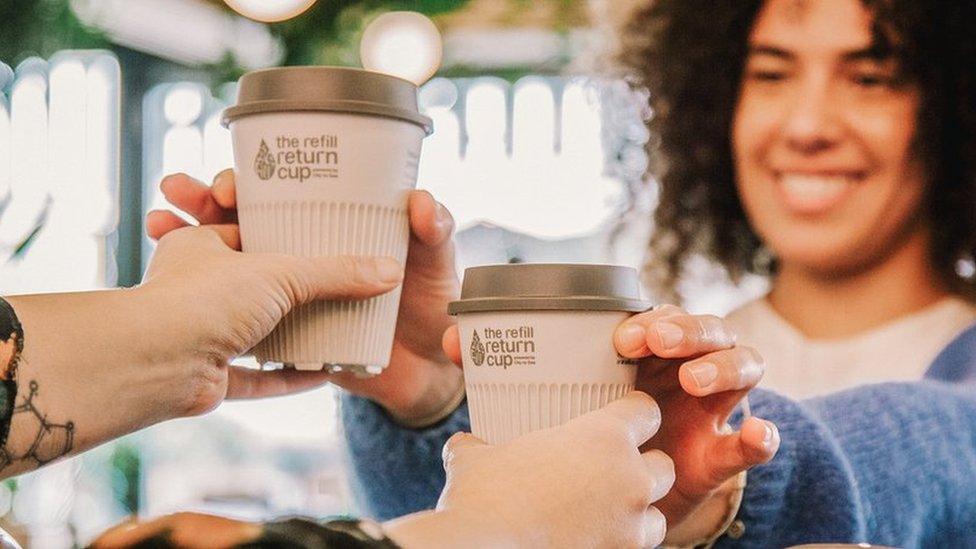 A picture of white coffee cups being handed to a woman