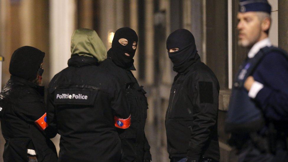 Masked police secure entrance to building in Schaerbeek during police operations in Brussels. 25 March 2016