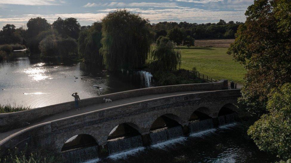 woman looking out on a chalk river in Sidcup from a bridge