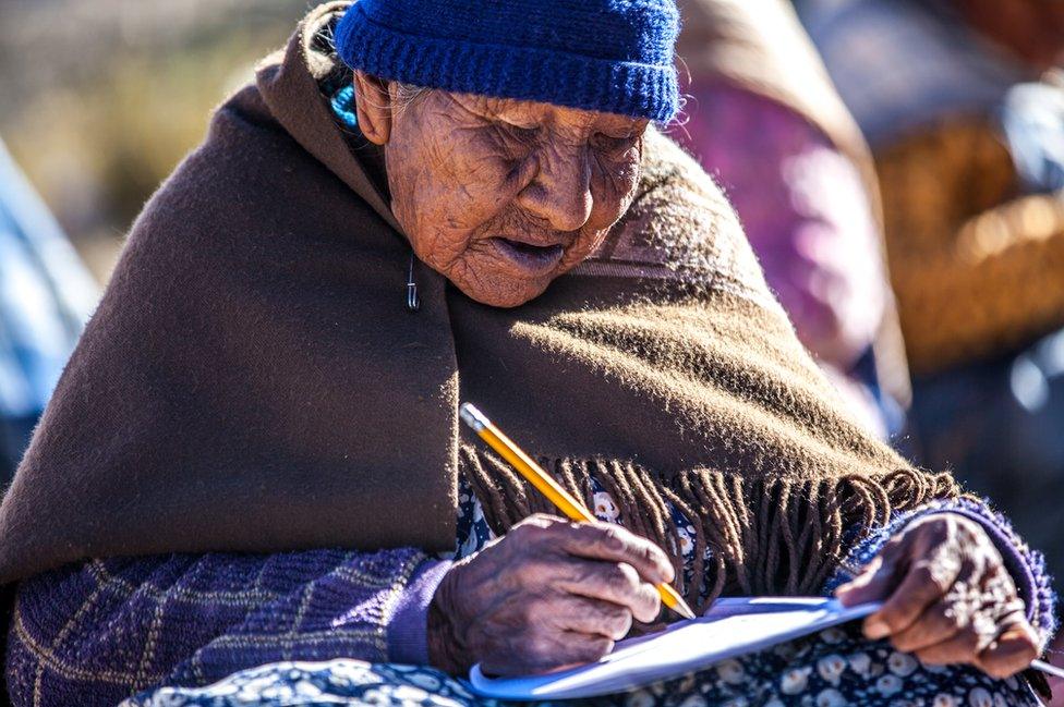 An elderly student practices writing in a notebook