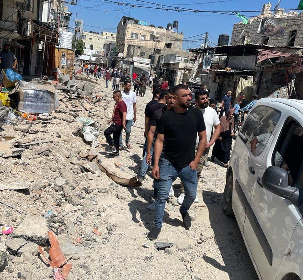 Palestinians inspect damaged vehicles, roads and vehicles in Jenin refugee camp, in the occupied West Bank, following a major Israeli military operation (5 July 2023)