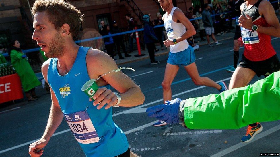 A runner grabs a cup of Gatorade as he runs on Lafayette Avenue during the 2016 TCS New York City Marathon,