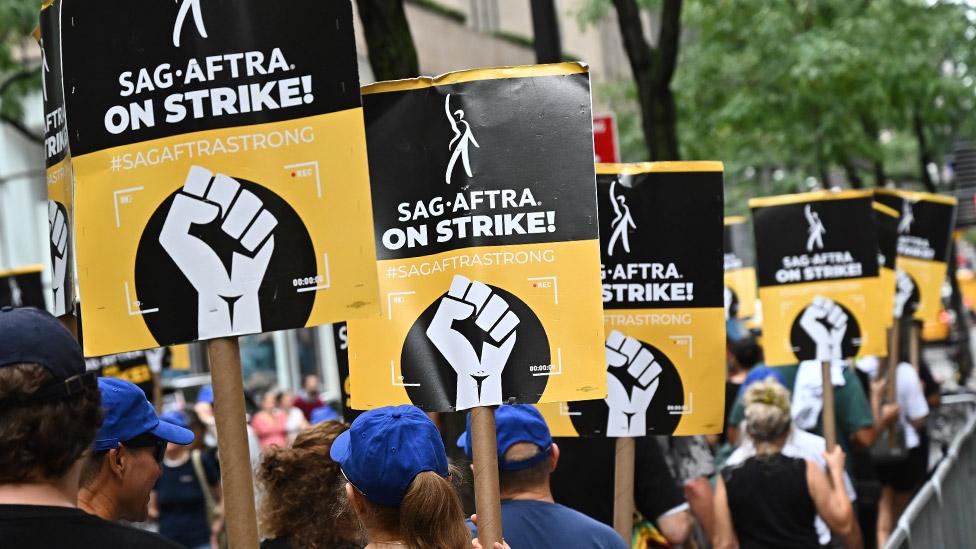 People holding up placards saying "Sag-Aftra on strike"