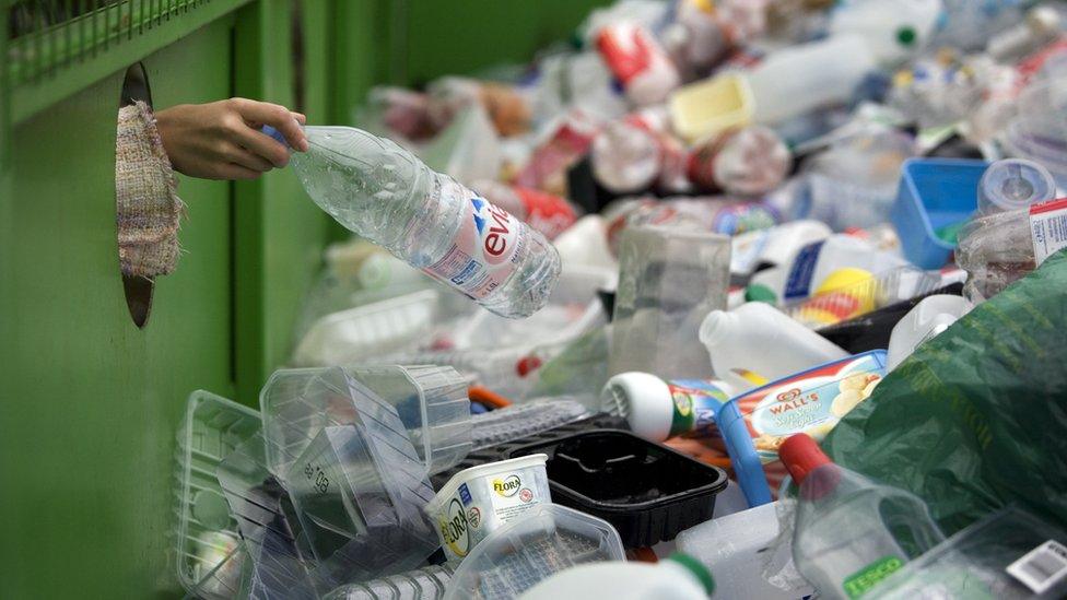 A woman puts plastic in a bin