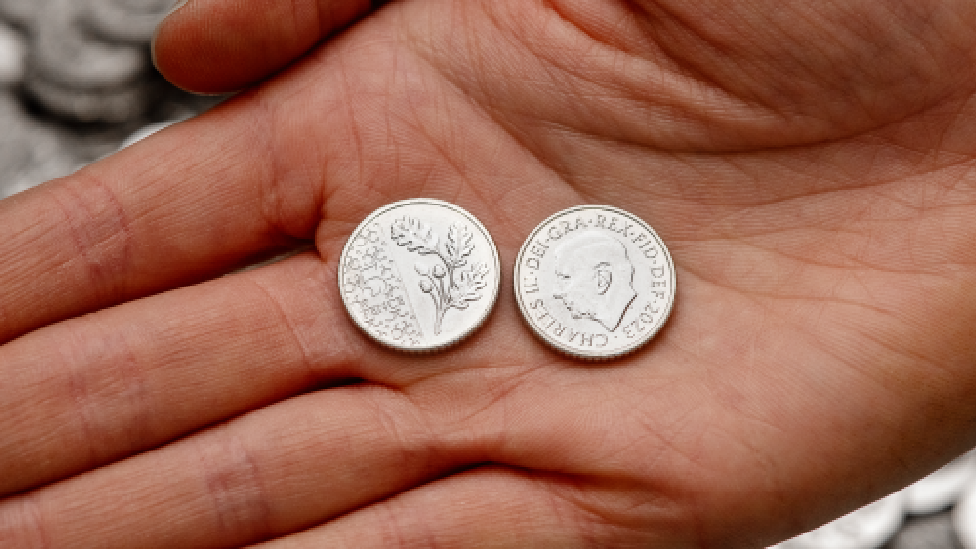 Close-up image of two 5p coins pictured on someone's hand, showing the front and reverse design.