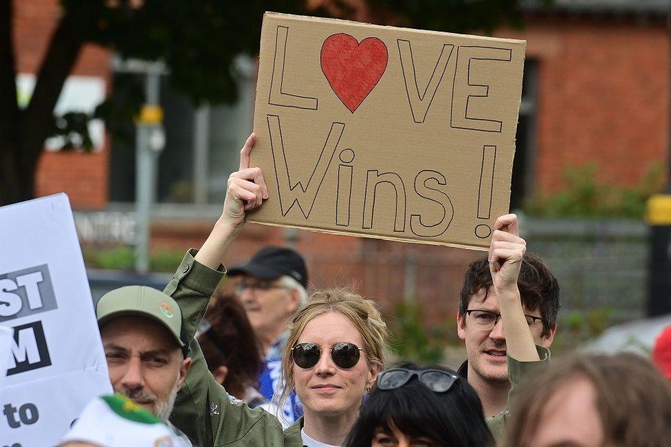 Anti racism rally Dunmurry, woman holding 'Love wins' sign