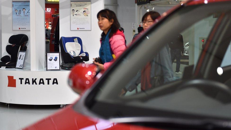 Woman walks past Takata stand