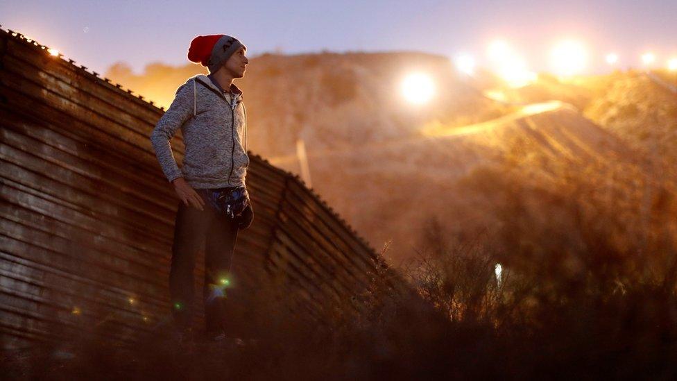 Kevin Jorge Gallardo Antunez, a migrant from Honduras, poses in front of the border wall