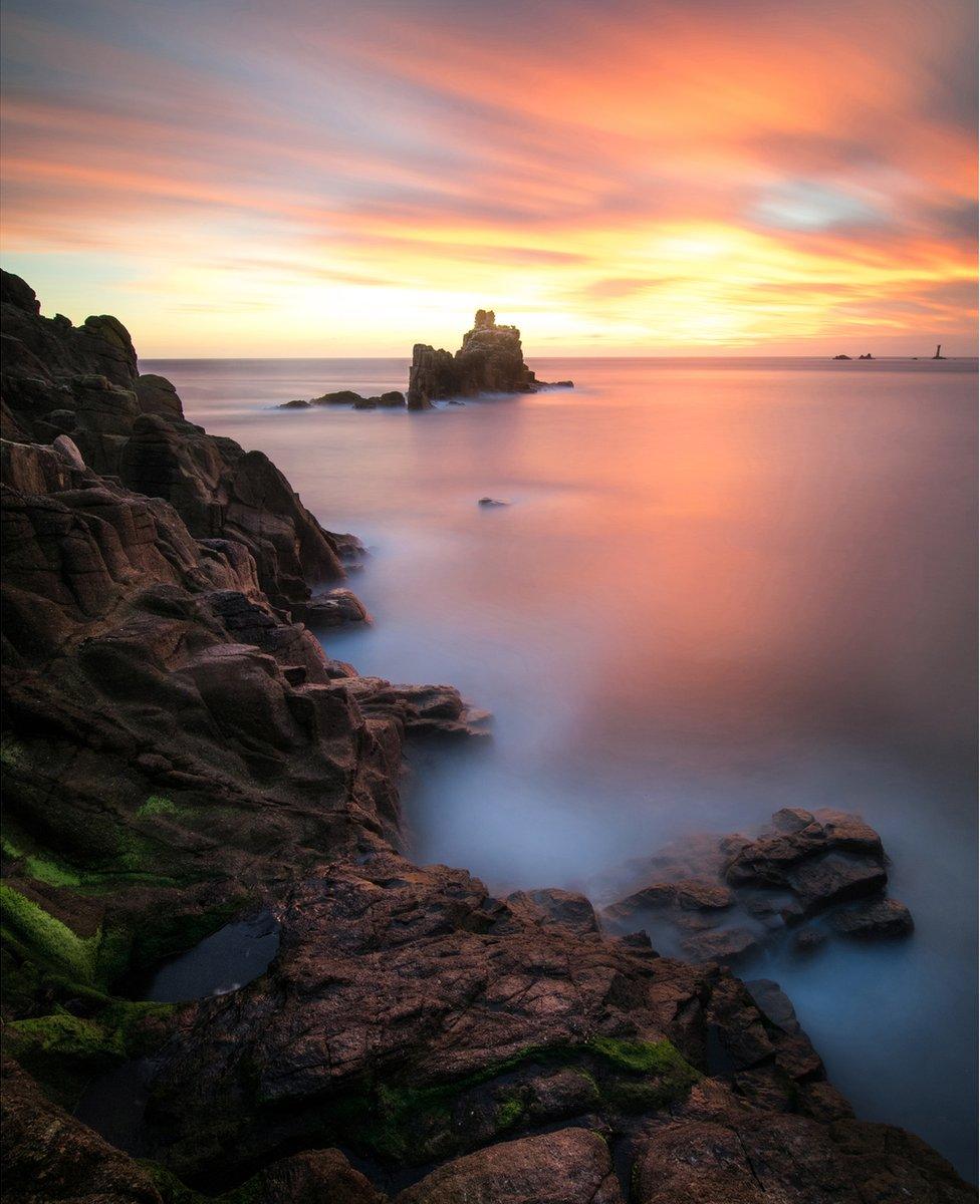 A picture of fog settling over a rocky hill by the sea