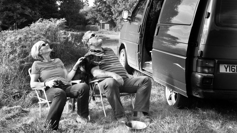 A couple watching red kites by the side of the road.