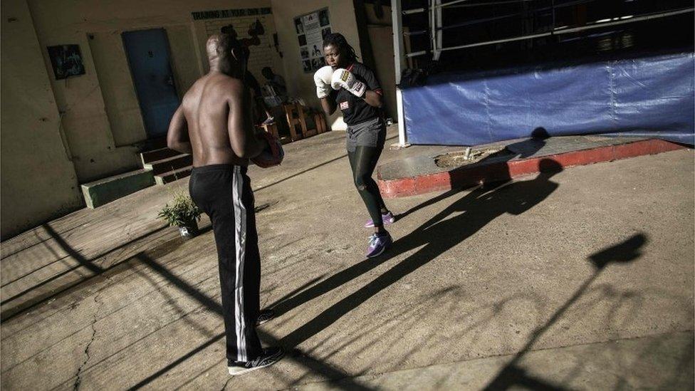Boxing trainer George Khosi(L) spars with amateur fighter Selina Mabunda (R) at the Hillbrow boxing club on March 2, 2016, in Johannesburg. The Hillbrow boxing club used to be a petrol station before being turned into a boxing gym in the dilapidated neighbourhood of Hillbrow.