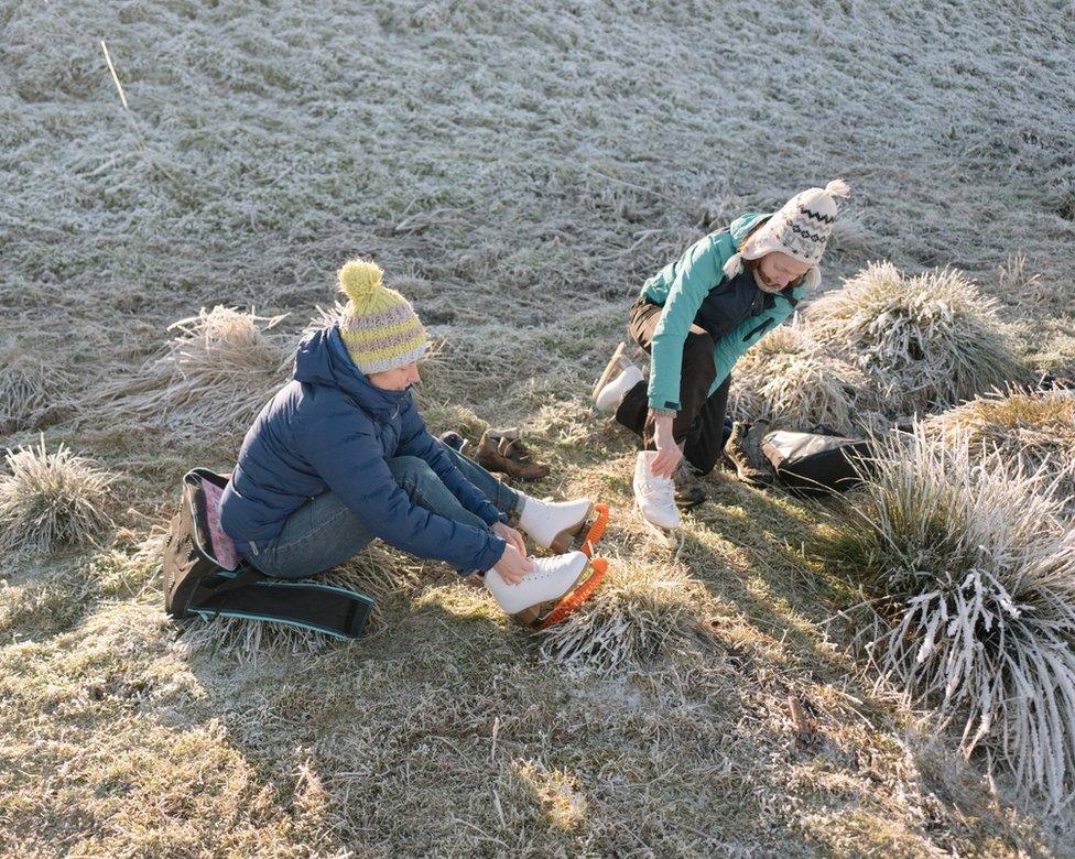 Skaters lace up their skates on the frozen grass before taking to the ice