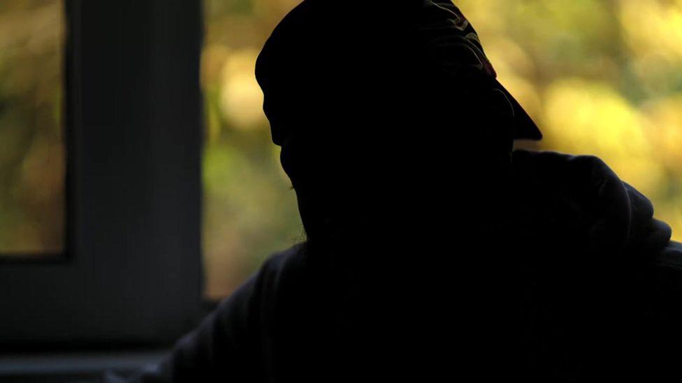 The man the BBC is calling Hakan, pictured in shadow so you cannot make out any of his features. He is wearing a backwards-facing cap.