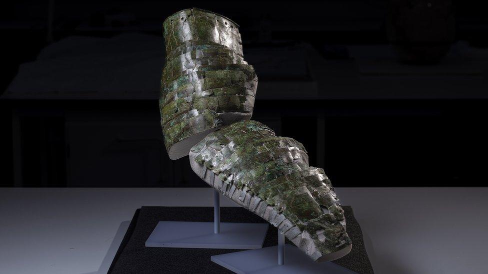 Image shows reconstructed arm guard on display - it is made up of lots of little parts which make it look similar to reptile skin