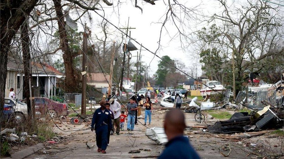 Residents walk down a street along Chef Menture Ave after a tornado touched down in the eastern part of New Orleans, Louisiana.