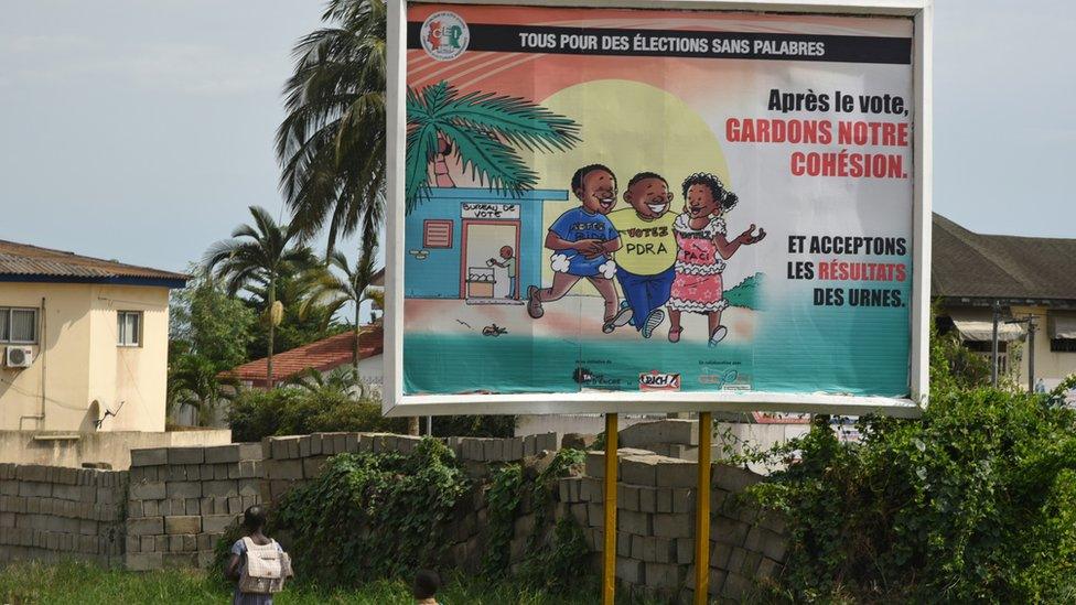 Children pass an Independent Electoral Commission (CEI) poster reading "All for an election without debate", "After the voting, keep our cohesion" and "accept the results of the ballot box" in Abidjan