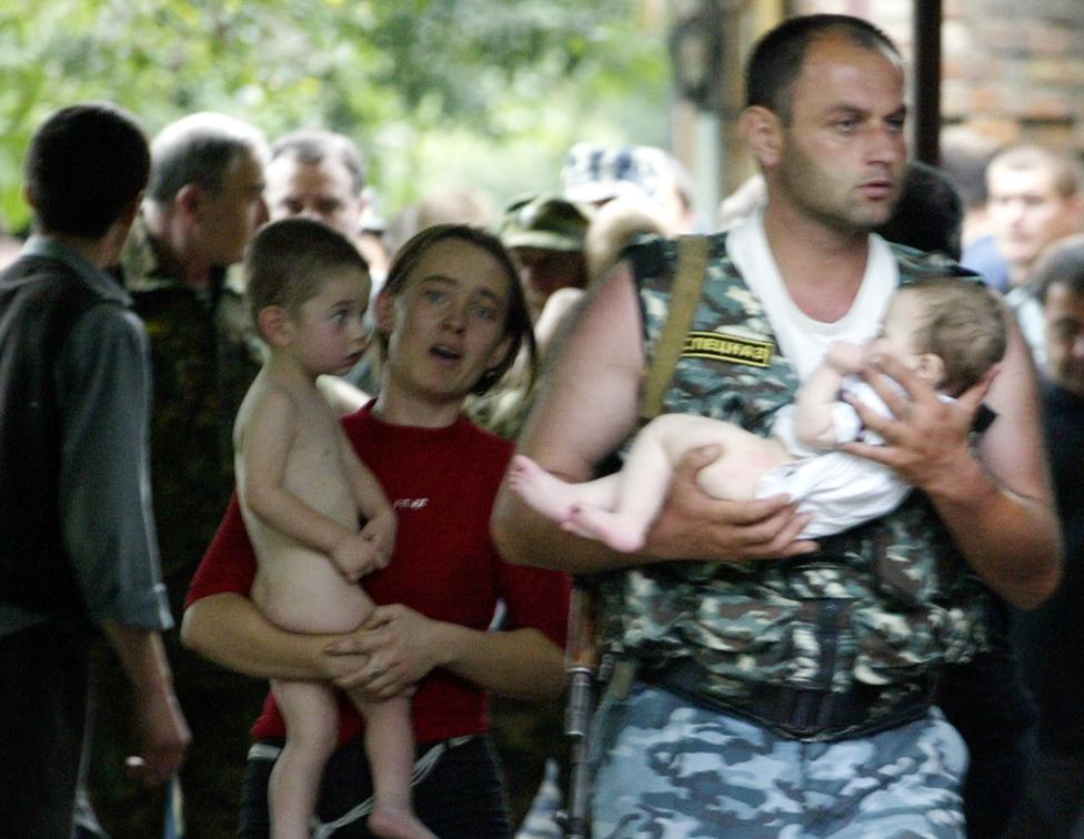 A police officer and a woman carry two recently released children near a school taken over by militants on September 2, 2004