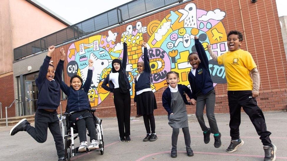 Children jumping in front of seagulls mural