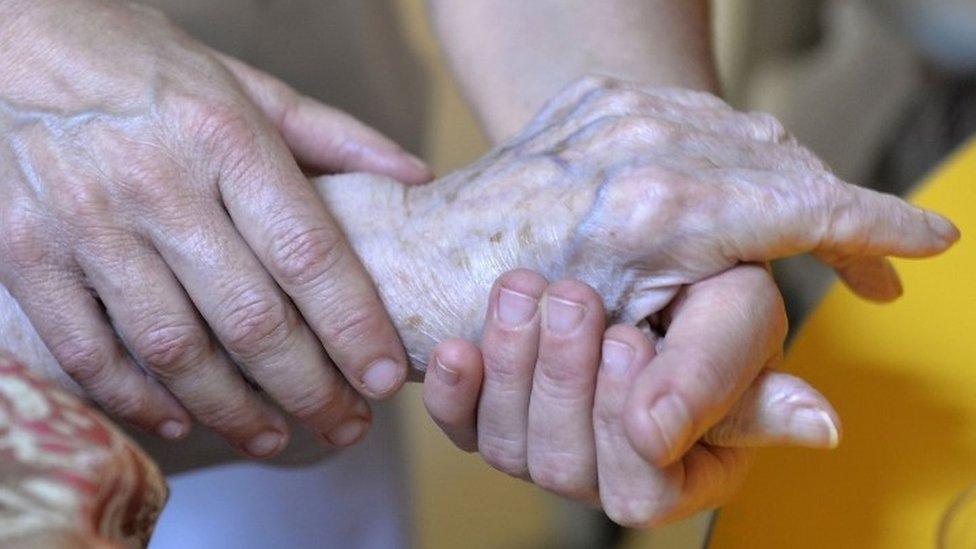 Elderly person's hand being held