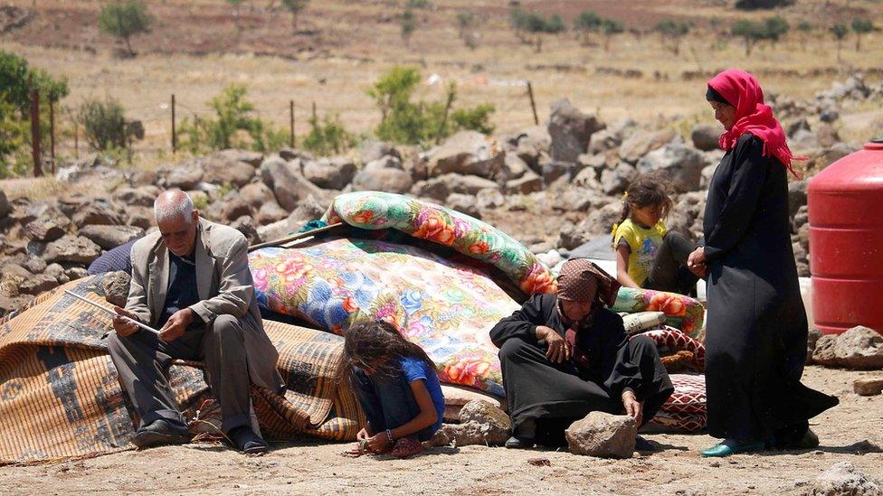 Displaced Syrian civilians from Deraa province wait at a makeshift camp in Quneitra province (22 June 2018)