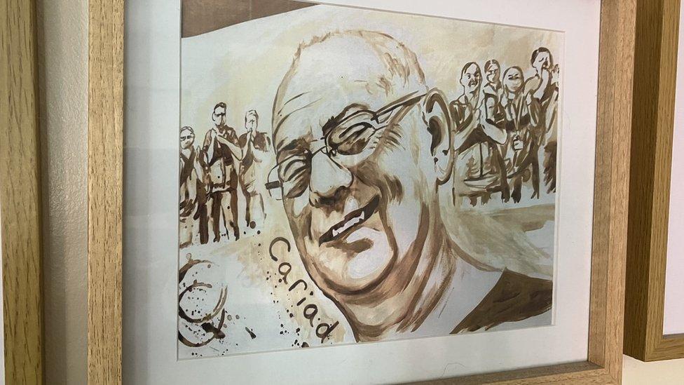 framed drawing of Gareth Roberts's face, smiling, with a crowd in the background clapping