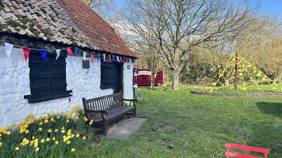 A building, daffodils and bunting in Thriplow, Cambridgeshire