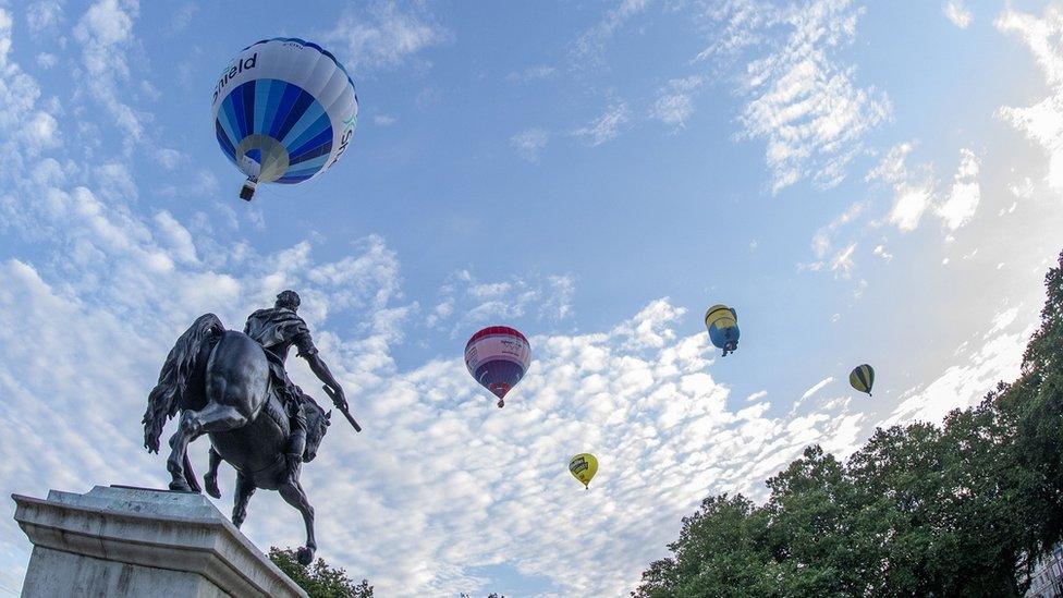 Balloons in the sky by the statue of William III in Queen Square, Bristol